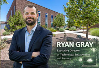 Ryan Gray standing on the campus under a tree
