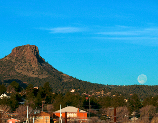 Thumb Butte with a full moon balancing on the edge