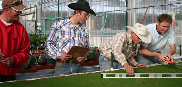 Man with cowboy hat using a level