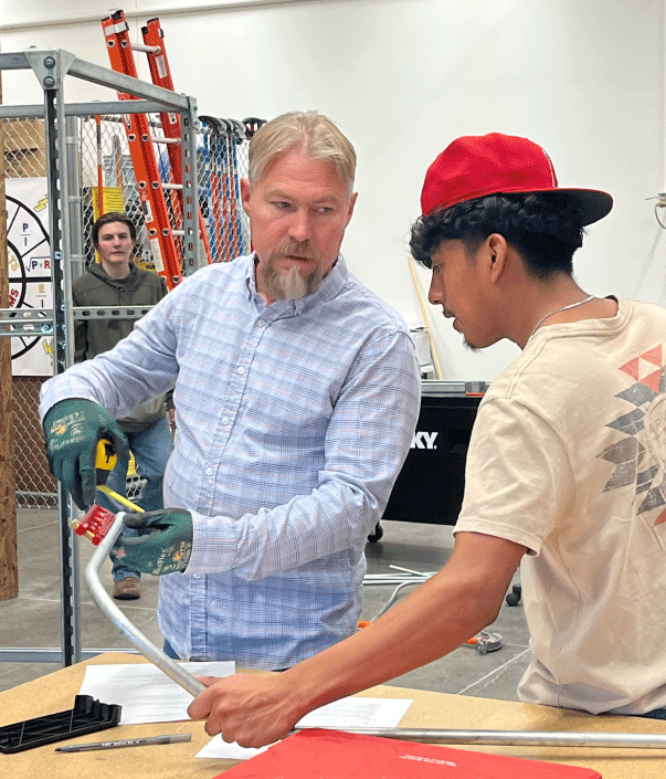 An electrician instructor demonstrates conduit bending techniques with a student in the Skilled Trades Center lab
