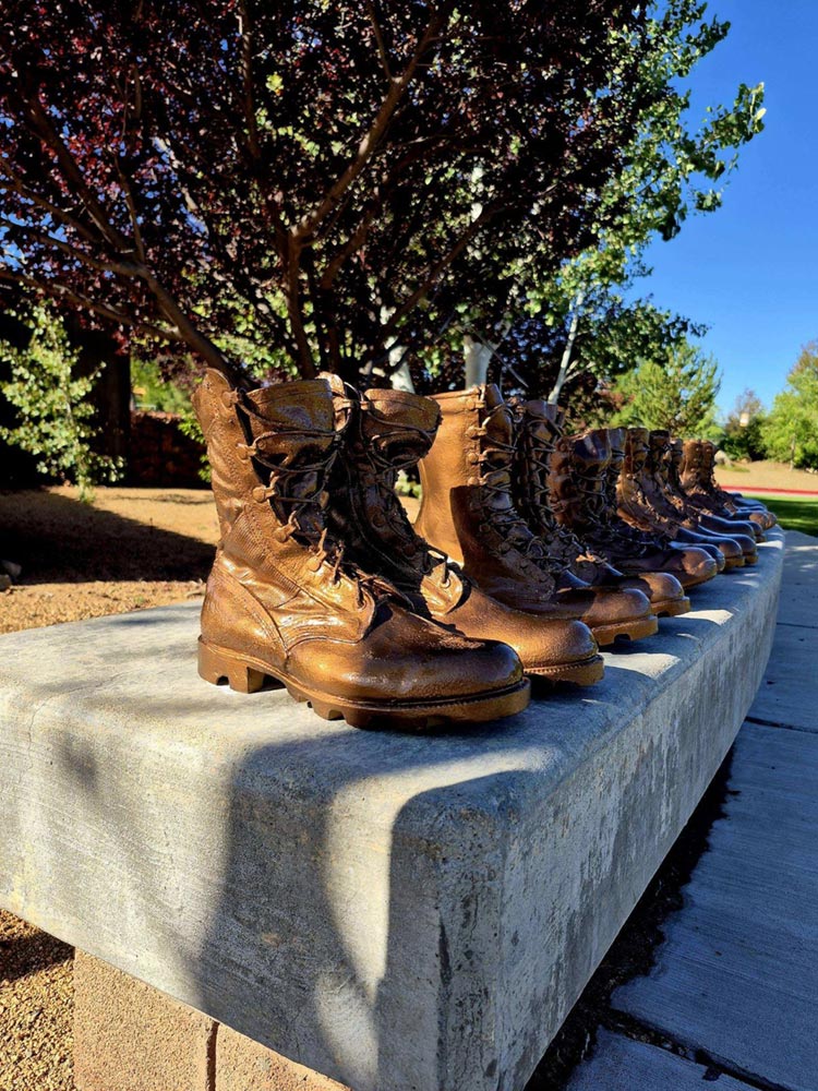 Angled view of memorial boots along the stone bench.